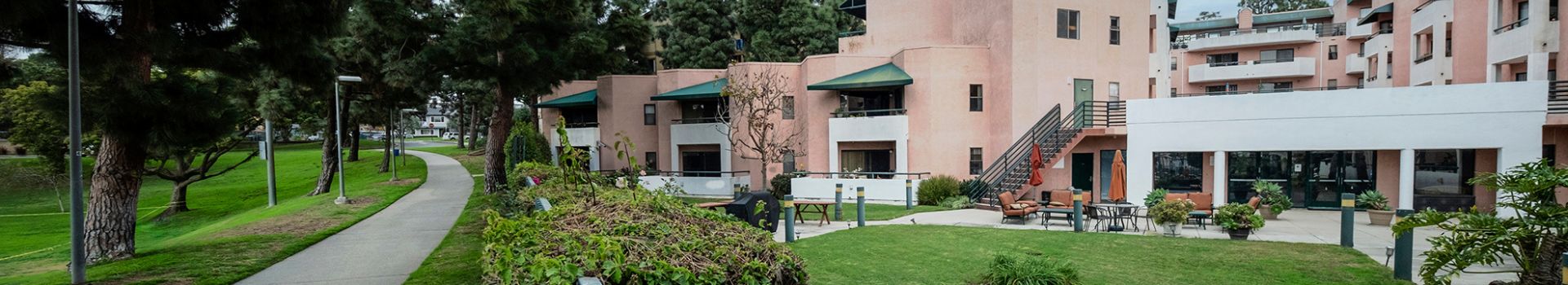 outside view of apartment building with concrete path and pine trees